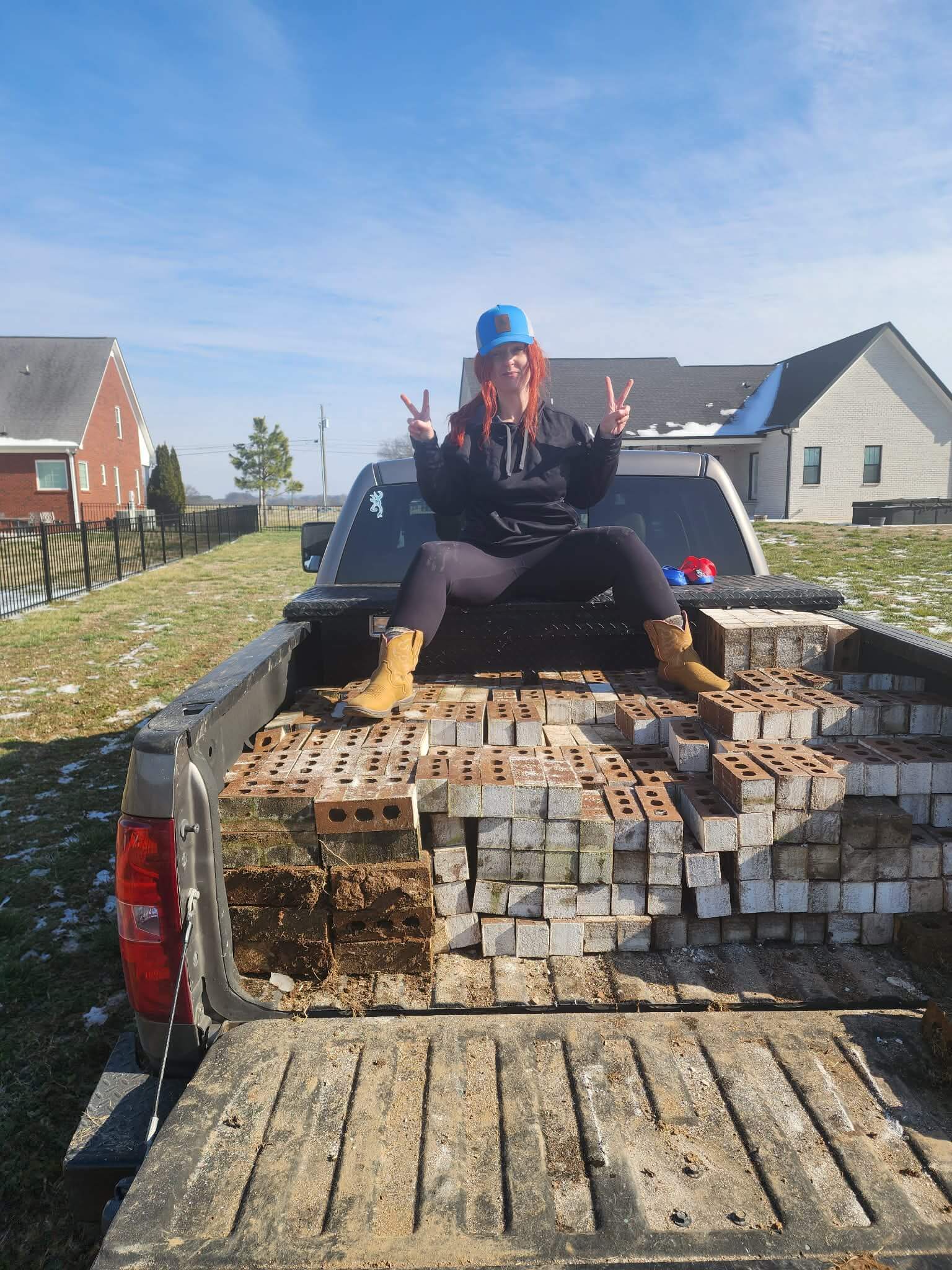 Rodeo Junk Removal team member sitting in truck bed after loading a full haul of bricks