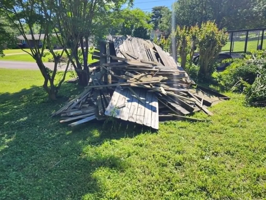 Before photo of privacy fence debris removal in Ardmore, TN with torn-down fence stacked in a backyard